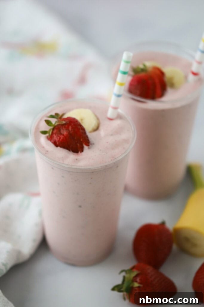 Two strawberry and banana protein smoothies with straws, ready to be enjoyed.