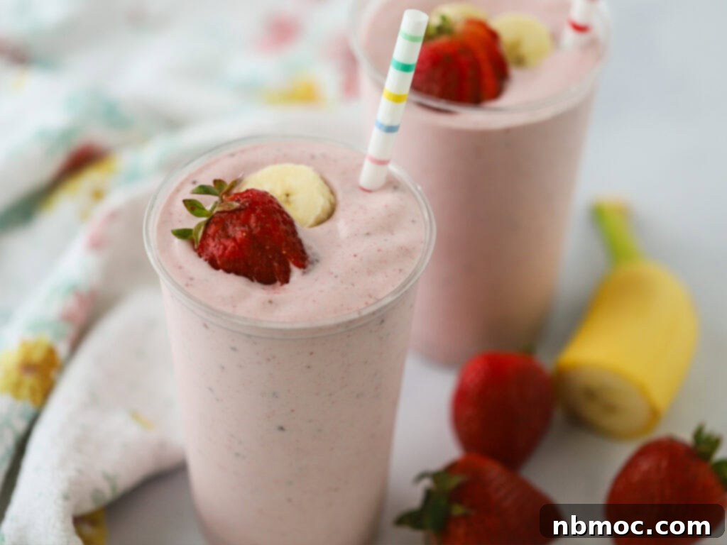 Strawberry banana smoothies with fresh strawberries and bananas artfully arranged in the background.