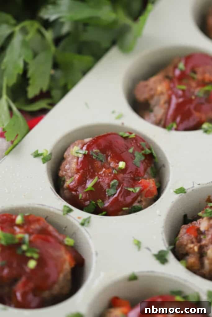 Perfectly baked mini meatloaves, glistening with a savory tomato and BBQ glaze, arranged appealingly in a muffin tin.