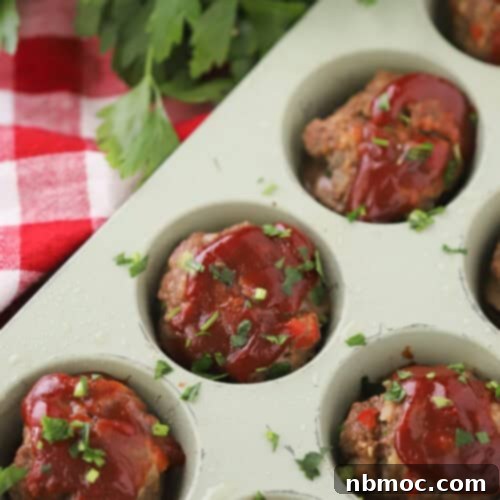 Delicious mini meatloaf with a savory glaze, served on a plate with fresh herbs.