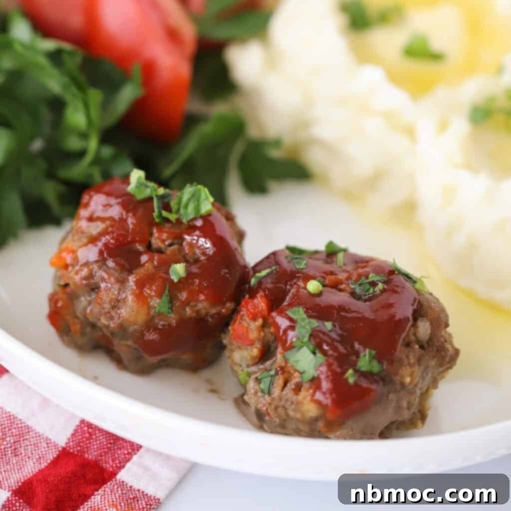 A single perfectly glazed mini meatloaf, presented on a pristine white plate, garnished with fresh herbs, ready to be enjoyed.