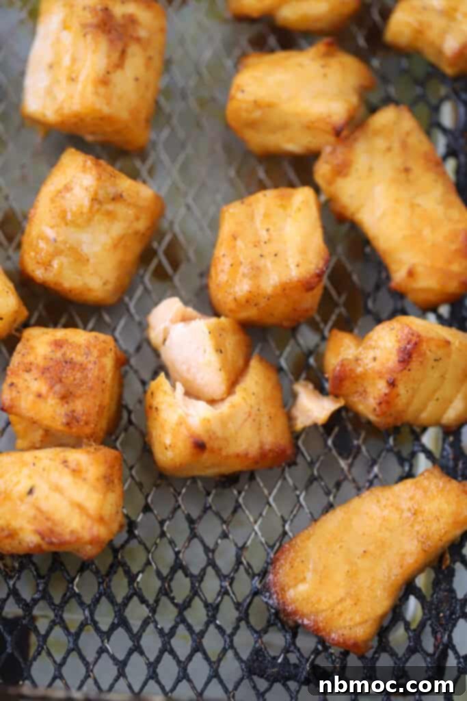 An air fryer basket filled with golden-brown, crispy salmon bites, ready to be served.