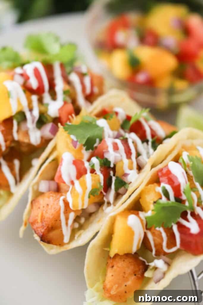 Crispy Air Fryer Salmon Tacos with vibrant peach salsa, fresh cabbage, and creamy lime crema, served on a rustic counter. A perfect healthy and flavorful weeknight meal.