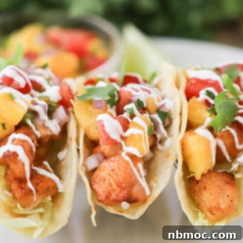 Close-up of a beautifully plated Air Fryer Salmon Taco, showcasing the peach salsa, salmon, and lime crema.