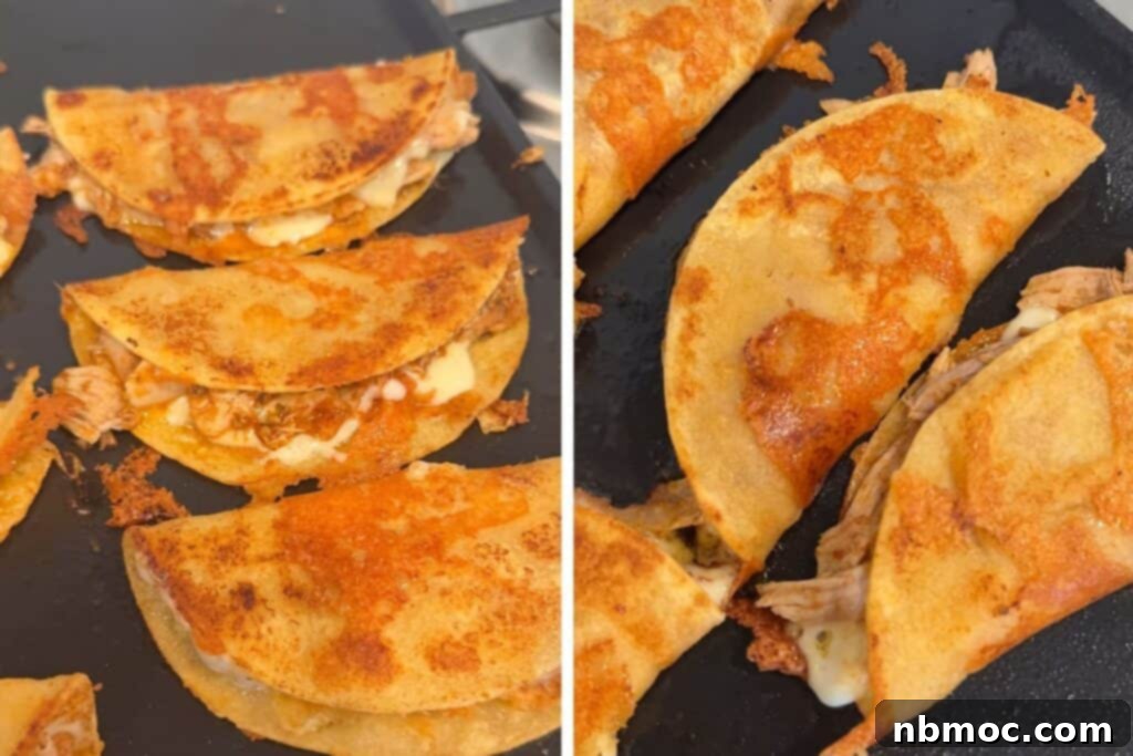 Several birria tacos cooking on a griddle, browning and crisping up.