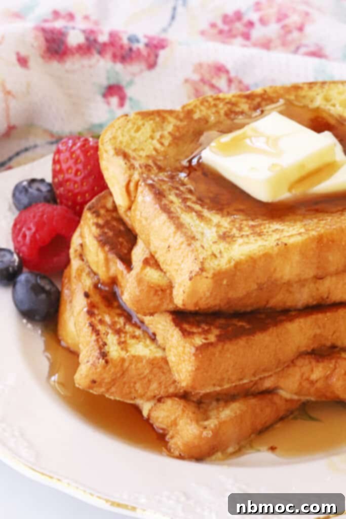 A plate with a stack of classic french toast topped with butter and syrup. 
