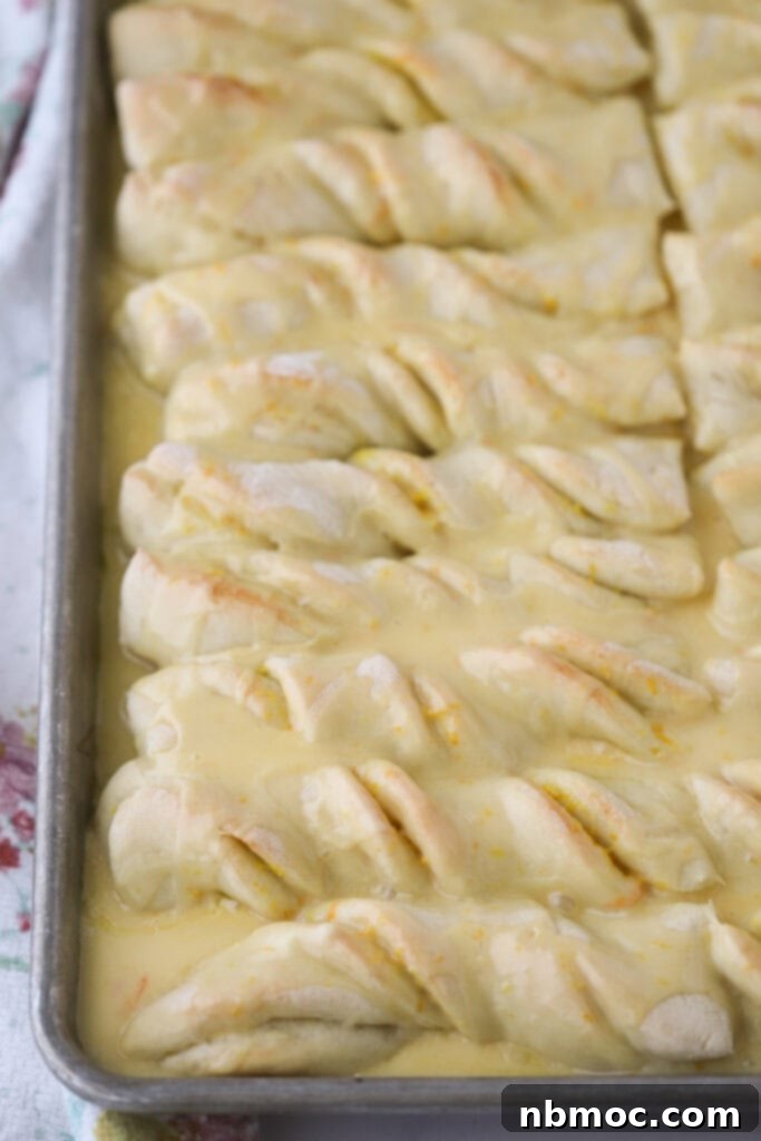 A baking sheet full of orange twist breadsticks covered in orange glaze.