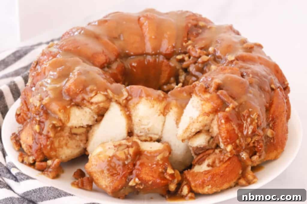 Gooey Caramel Pecan Pull-Apart Bread 5 A beautiful homemade caramel pecan monkey bread on a white serving plate, garnished with extra pecans.