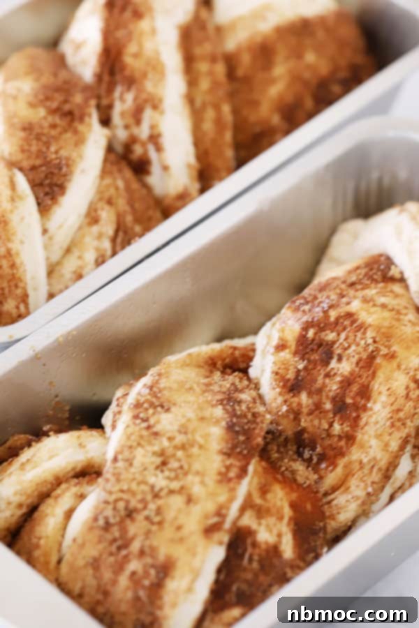 Homemade Cinnamon Twist Bread topped with vanilla icing, fresh from the oven, served in loaf pans.
