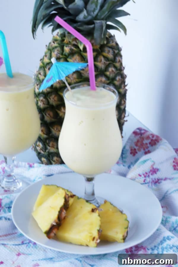 A glass full of this Disney Dole Whip recipe garnished with a little paper umbrella and straw, ready to be enjoyed.