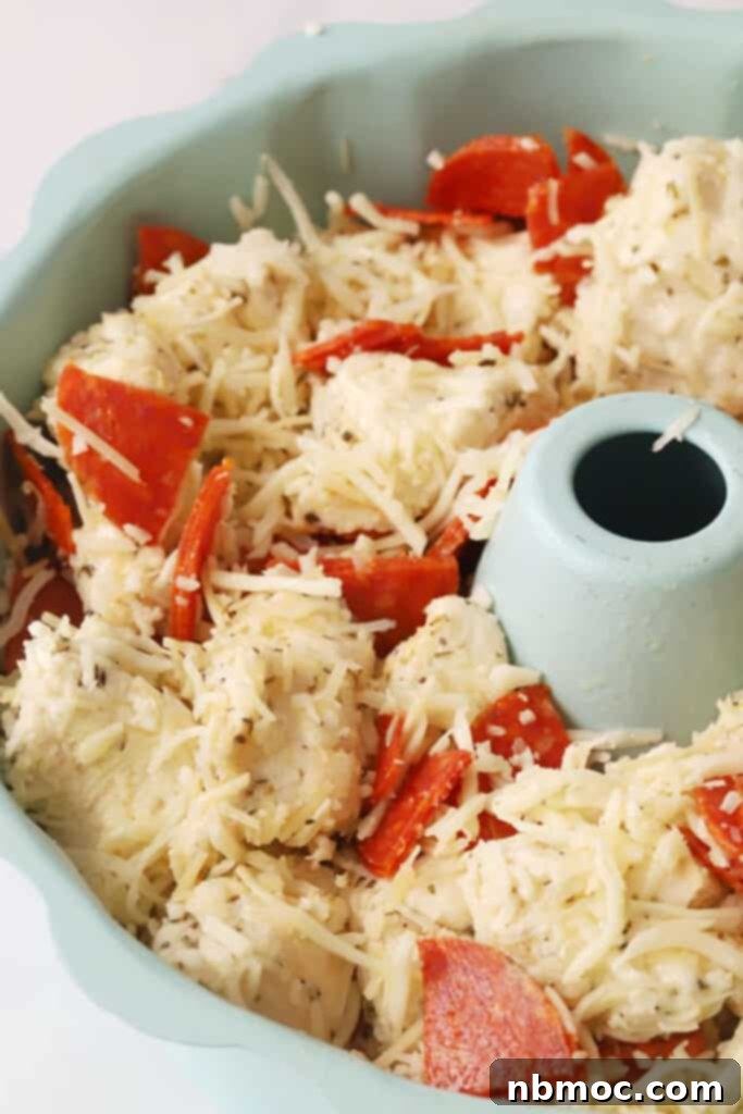 Unbaked pepperoni monkey bread pizza mixture nestled in a bundt pan, awaiting its transformation in the oven.
