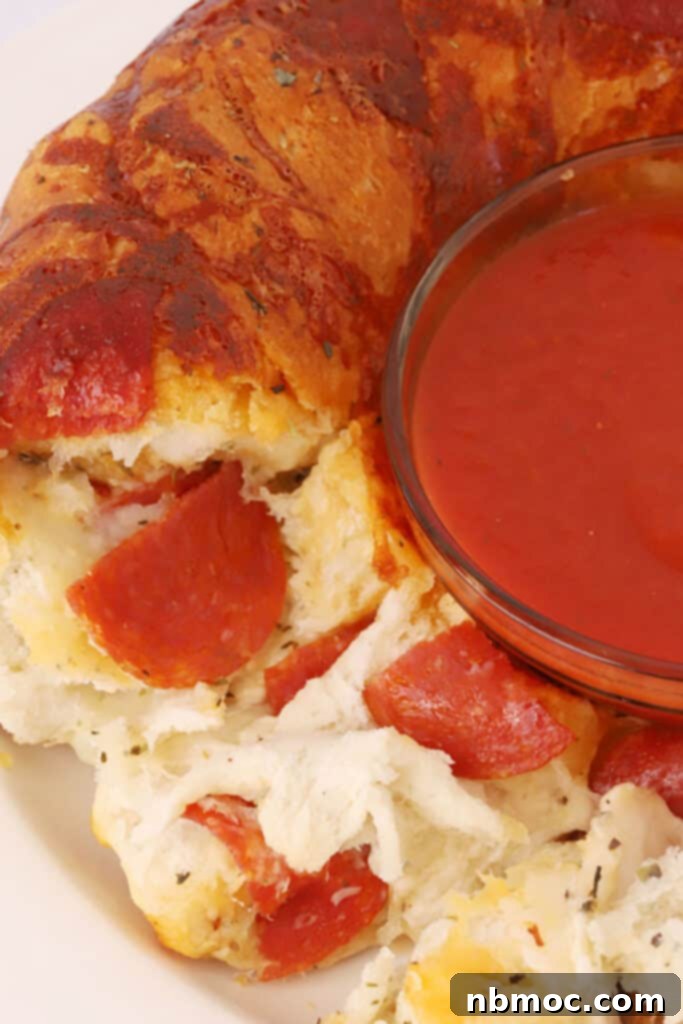 A top-down view of Monkey Bread pizza with a small bowl of marinara dipping sauce perfectly placed in the middle of the bundt-shaped bread.
