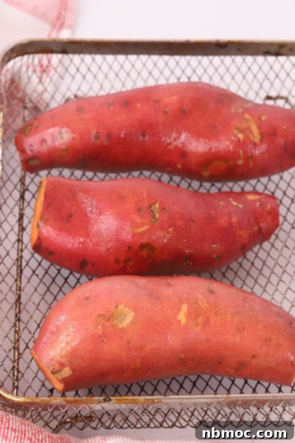 Golden Air Fryer Sweet Potatoes 3 Raw sweet potatoes placed neatly in an air fryer basket, ready for cooking.