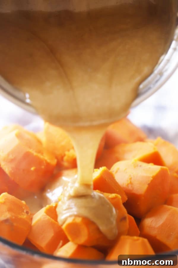 Golden Yam Bake with Toasted Marshmallow Topping 3 Pouring the brown sugar caramel mixture over cooked sweet potatoes in a mixing bowl.