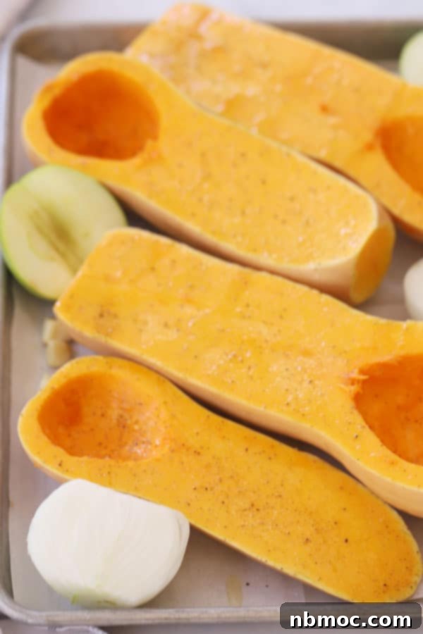 Golden Curry Squash Velouté 3 butternut squash halves for making curry squash soup laid out flat on a baking sheet with apples and onions.