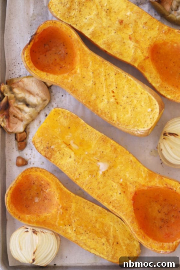 Golden Curry Squash Velouté 4 Roasted butternut squash halves, apples, garlic, and onions on a baking sheet.