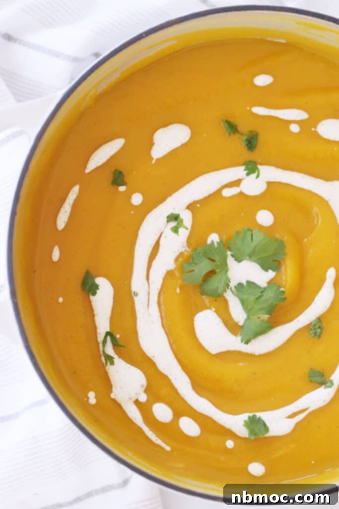 Roasted acorn squash soup in a bowl, garnished with sour cream and fresh cilantro.