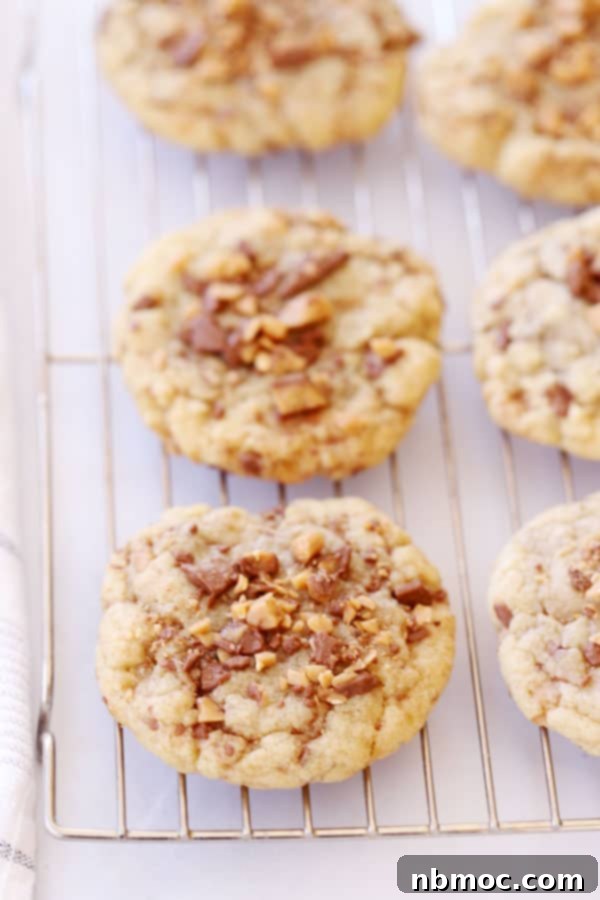 English Toffee Crunch Cookies 4 Freshly baked Heath toffee cookies cooling on a wire rack, ready to be enjoyed.