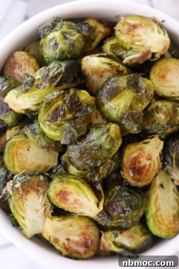 Golden Roasted Brussels Sprouts 2 A bowl full of crispy roasted brussels sprouts, garnished with cheese and herbs.