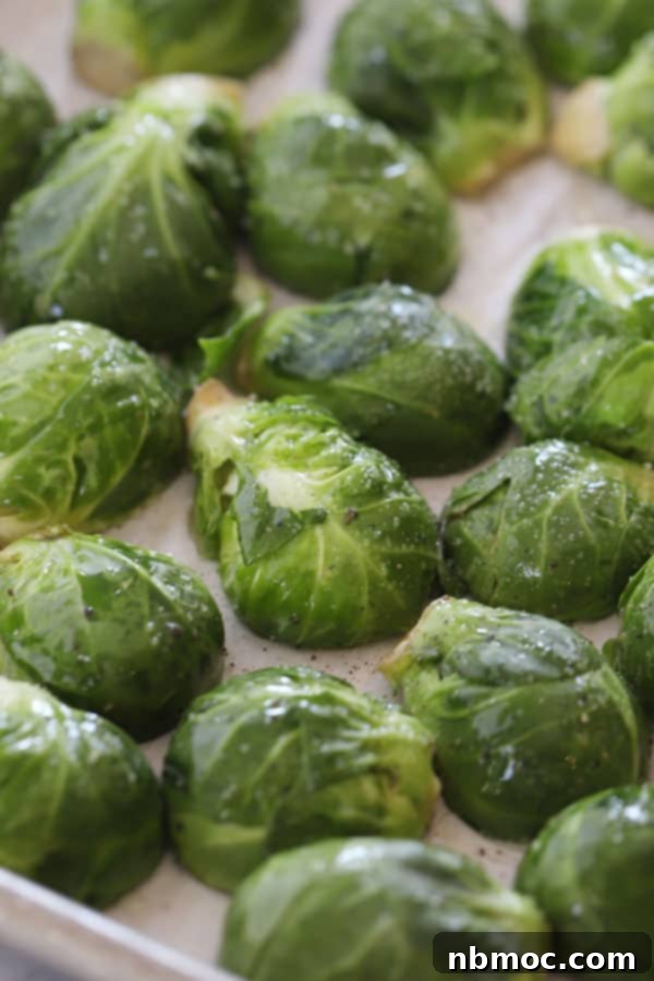 Golden Roasted Brussels Sprouts 4 Brussels sprouts ready to roast on a baking sheet in the oven, with the cut side down.