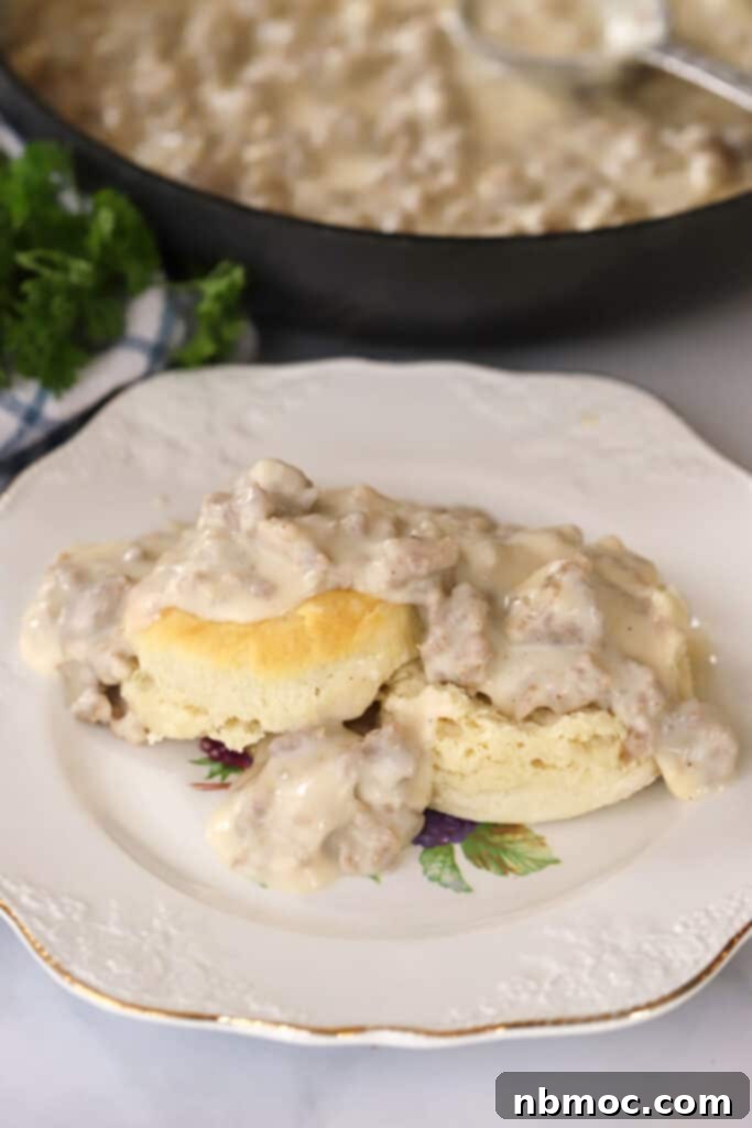 A plate with sausage gravy on top of homemade biscuits, perfectly golden brown and fluffy.