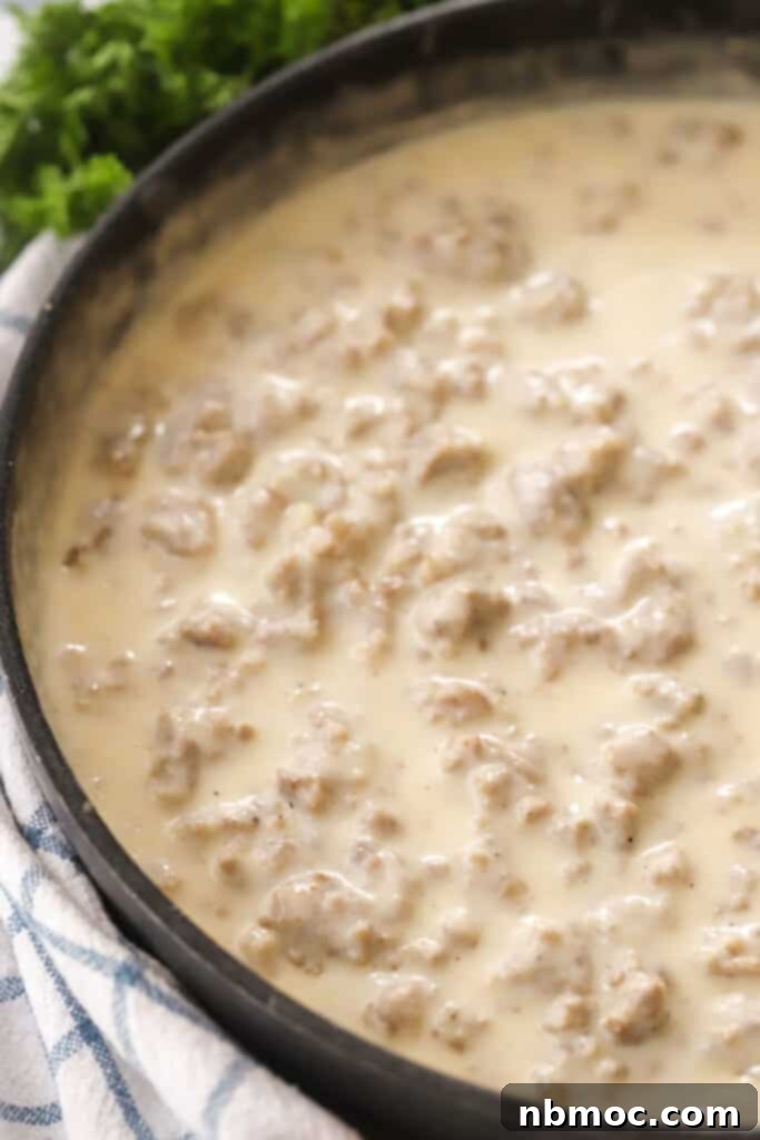 Creamy, thick sausage gravy bubbling gently in a non-stick pan, ready to serve.