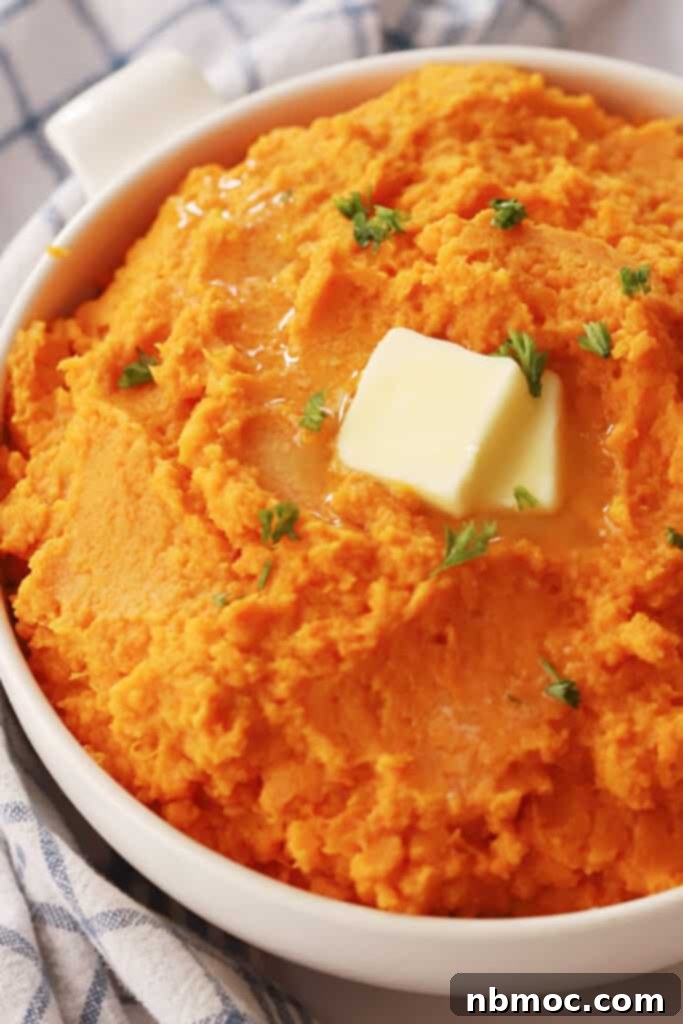 A serving dish full of mashed sweet potatoes topped with butter.