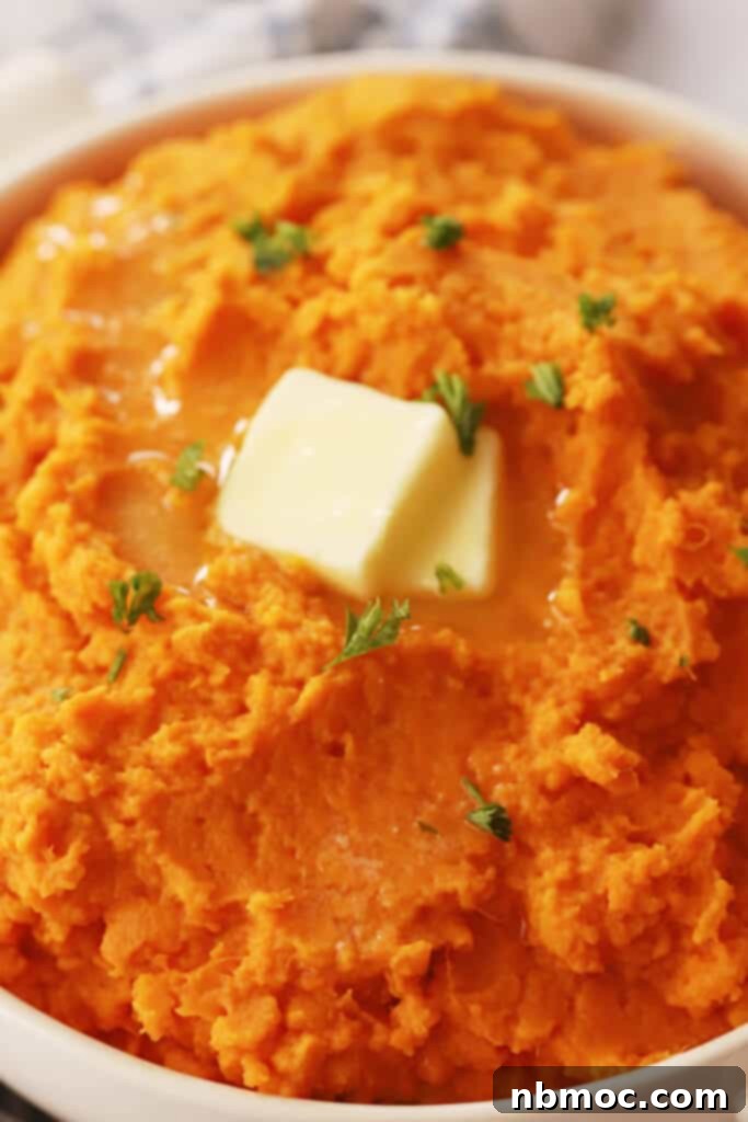 mashed sweet potatoes in a bowl topped with butter and parsley.