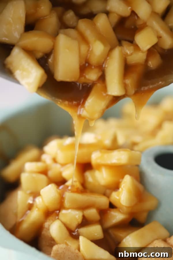 Warm Spiced Apple Monkey Bread 4 Pouring the caramel apple mixture over cinnamon sugar-coated biscuit pieces in a bowl for apple cinnamon monkey bread.