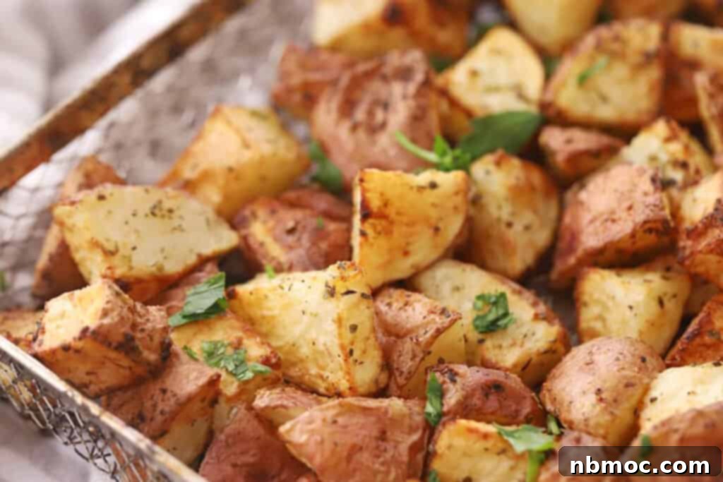 Crispy Air Fryer Red Potatoes 3 red potatoes in air fryer basket with fried red potatoes topped with fresh chopped parsley.
